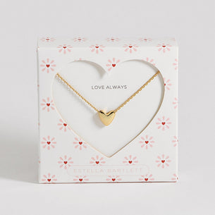 Gold heart-shaped necklace on a decorative card with 'Love Always' text on a light gray background