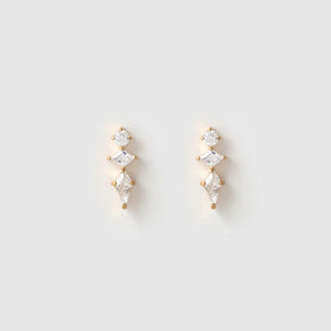 A pair of gold drop earrings with three clear marquise-cut gemstones stacked vertically, set against a plain light gray background.