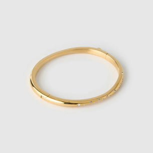 Gold bracelet on a light gray background