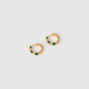 Gold hoop earrings with green beads on a light gray background